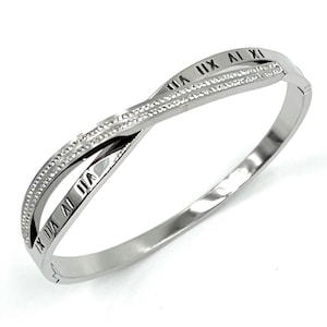 May include: A silver bangle bracelet in an infinity symbol design. The bracelet has Roman numerals and a row of small, sparkling stones. The bracelet is made of a shiny, metallic material.