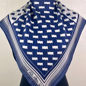 Puede incluir: Un pañuelo de seda azul y blanco con estampado, con un borde blanco y el texto "Pierre Cardin" en la esquina inferior derecha.