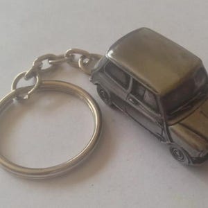以下が含まれることがあります： クラシックなミニクーパーのミニチュアモデルが付いたシルバーメタルキーチェーン