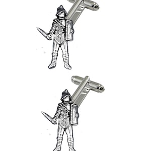 May include: A pair of silver cufflinks featuring a pewter gladiator figurine with a sword and shield.