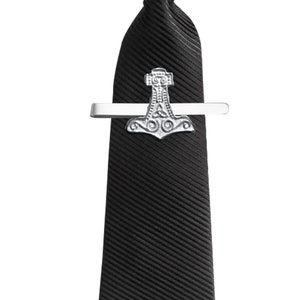 May include: A black tie with a silver tie clip featuring a Mjolnir, the hammer of Thor, design.