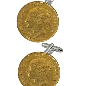 Puede incluir: Un par de gemelos de oro con una réplica de una moneda de oro británica de 1870. Los gemelos están hechos de plata y tienen un acabado pulido.