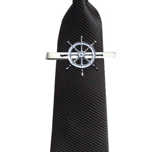 May include: A black striped tie with a silver tie clip featuring a ship's wheel design.
