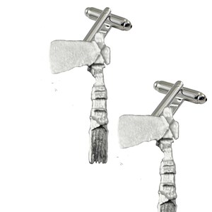 May include: A pair of silver cufflinks featuring a detailed design of a tomahawk.