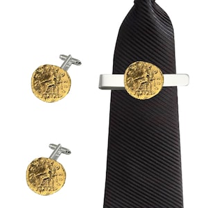 Puede incluir: Un juego de gemelos y pasador de corbata de oro con una réplica de una antigua moneda romana. El pasador de corbata es de plata y la corbata es negra.