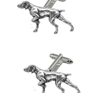 May include: A pair of silver cufflinks featuring a detailed German Shorthaired Pointer dog design. The cufflinks are made of metal and have a polished finish.