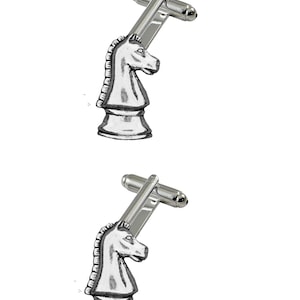 Puede incluir: Un par de gemelos plateados con un diseño de caballero de ajedrez. El caballero está representado en una forma clásica y estilizada con una crin levantada y una base detallada.