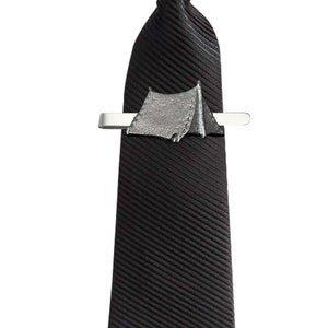 May include: A black tie with a silver tie clip featuring a tent design.