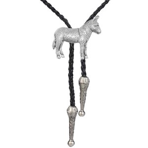 May include: A silver donkey bolo tie with a black braided leather cord. The bolo tie has a silver tip on each end.