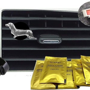 May include: Car air freshener set with a silver dachshund dog design on a black disc, attached to a car vent. Includes gold foil packets with Chinese and English text, and a black clip for attachment.