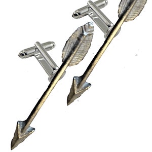 May include: A pair of silver cufflinks with arrowhead designs. The arrowheads are silver with a gold finish and have a feather detail.