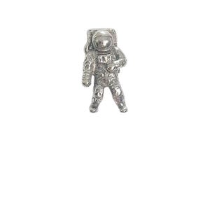 Op de afbeelding: Een kleine, zilverkleurige astronautenfiguur. De astronaut is afgebeeld in een staande pose, gekleed in een gedetailleerd ruimtepak met helm en rugzak. Het beeldje is een miniatuurweergave van een ruimteverkenner.
