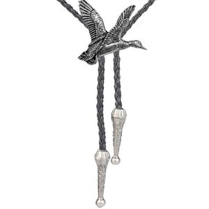 May include: A silver bolo tie featuring a detailed flying duck design. The tie has a black braided cord with silver tips.