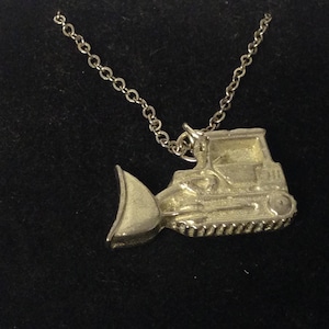 May include: A silver necklace with a pendant shaped like a bulldozer. The pendant is detailed and has a realistic design.