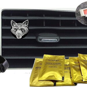 May include: A set of five gold car air fresheners with different scents. The scents are Peach Flavor, Lavender, Lemon, and two others in Chinese characters. The air fresheners are packaged in individual foil pouches. A black plastic car vent clip is included. A silver fox head is shown in the background.