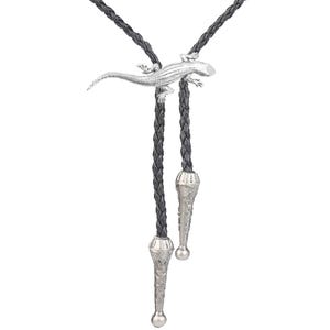 Op de afbeelding: Een zwarte gevlochten bolo tie met een zilveren hagedisbedel en zilveren uiteinden.