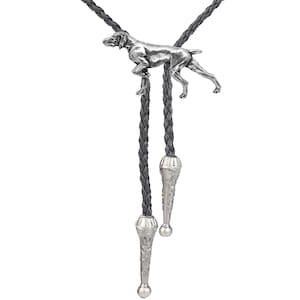 May include: A silver bolo tie featuring a detailed, three-dimensional German Shorthaired Pointer dog figurine. The tie is made of black braided leather with silver tips.