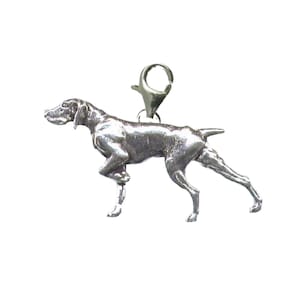 Op de afbeelding: Een zilveren bedel in de vorm van een Duitse Kortharige Wijzer. De bedel is bevestigd aan een zilveren springring.