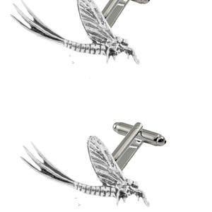 May include: A pair of silver cufflinks featuring a detailed dragonfly design. The cufflinks are made of metal and have a polished finish.