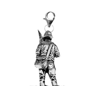 May include: Silver charm of a fisherman holding a fishing rod and wearing a backpack. The charm has a lobster clasp for attaching to a bracelet or necklace.