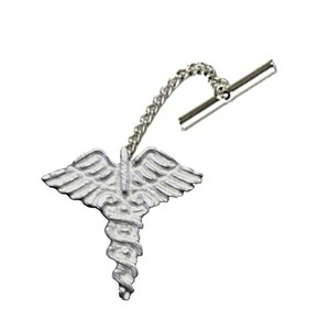 Op de afbeelding: Een zilverkleurige reversspeld met het Caduceus-symbool, een staf met twee slangen en vleugels. De speld is verbonden met een ketting en een staafje voor een veilige bevestiging. Het ontwerp is gedetailleerd en driedimensionaal.