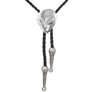 May include: A silver alien head bolo tie with black braided leather cord and silver tips.