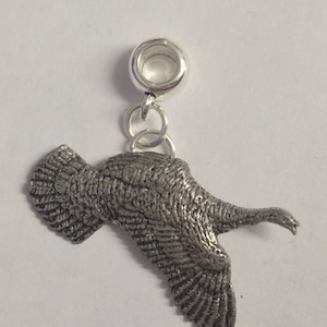 Puede incluir: Encanto de plata de un pavo en vuelo. El encanto tiene un diseño detallado y está unido a una cuenta de plata.