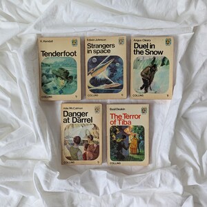May include: A collection of five vintage paperback books with illustrated covers. Titles visible are "Tenderfoot," "Strangers in Space," "Duel in the Snow," "Danger at Darrel," and "The Terror of Tiba." The books are arranged on a white background.