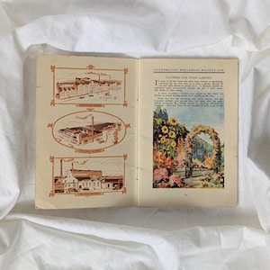 May include: Open vintage book with illustrations and text. The left page features three sepia-toned drawings of buildings. The right page displays a color illustration of a flower archway with the text "FLOWERS FOR YOUR GARDEN".