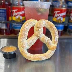 May include: A soft pretzel with salt sprinkled on top, a small container of mustard, and a glass of pink lemonade with a straw.