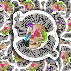 May include: A sticker featuring a skull with colorful worms crawling in and out of its eye sockets and nose. The text "The Worms Crawl In The Worms Crawl Out" is written on a banner around the skull.