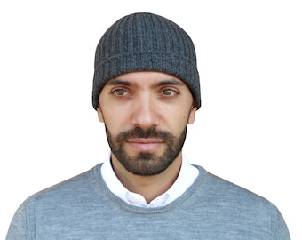 May include: A man wearing a grey knitted beanie and a grey jumper.