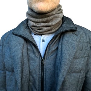 Könnte beinhalten: Eine graue Reißverschlussjacke mit einem grauen Strick-Halswärmer. Die Jacke hat ein gestepptes Design.
