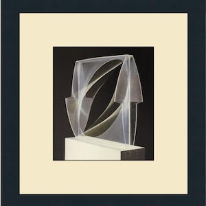 以下が含まれることがあります： 黒い背景に白い台座の上に置かれた、幾何学的な形をした銀色の抽象彫刻。金属とガラスでできている。