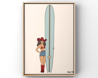 May include: A framed art print featuring a cartoon illustration of a woman in a red cowboy hat and bikini, denim shorts, and red boots, leaning against a light blue surfboard with a brown stripe. The artwork has a vintage aesthetic.