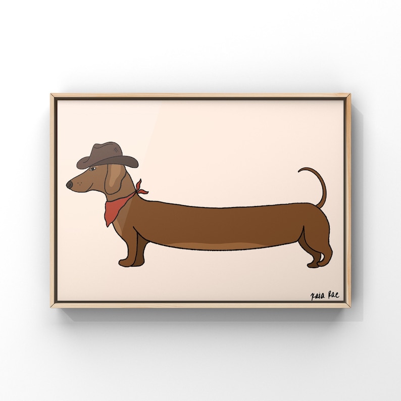 May include: A brown dachshund wearing a brown cowboy hat and a red bandana. The dog is standing on a light peach background. The image is signed "Gaia Rae" in the bottom right corner.