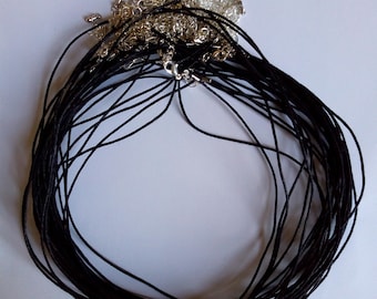 May include: A pile of black cord necklaces with silver clasps. The cords are bundled together and the clasps are visible at the top of the pile.