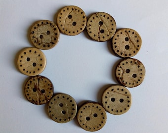 May include: A set of ten brown coconut shell buttons with two holes each. The buttons are arranged in a circle on a white background.