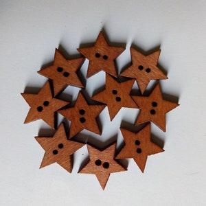 May include: Ten wooden star-shaped buttons in a warm brown hue. Each button features two small black holes for sewing. The buttons are arranged in a circular pattern against a white backdrop, ideal for craft projects.