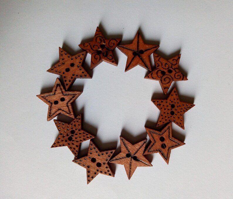 May include: A circular arrangement of wooden star-shaped buttons. Each button is a warm brown colour with a star shape and two holes for sewing. Some stars have decorative etched patterns.