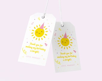 May include: Two white gift tags with a yellow sun illustration wearing a party hat. The tags have the text "Thank you for making my birthday so bright!" and "LOVE, MARGOT" in a playful font. Confetti and streamers decorate the tags.