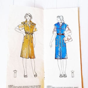 Op de afbeelding: Twee mode-illustraties van vrouwen die jurken dragen. De eerste jurk is een gele, mouwloze jurk met een riem. De tweede jurk is een blauwe, mouwloze jurk met een wit-blauw geruit overhemd eronder. Beide jurken hebben zakken.
