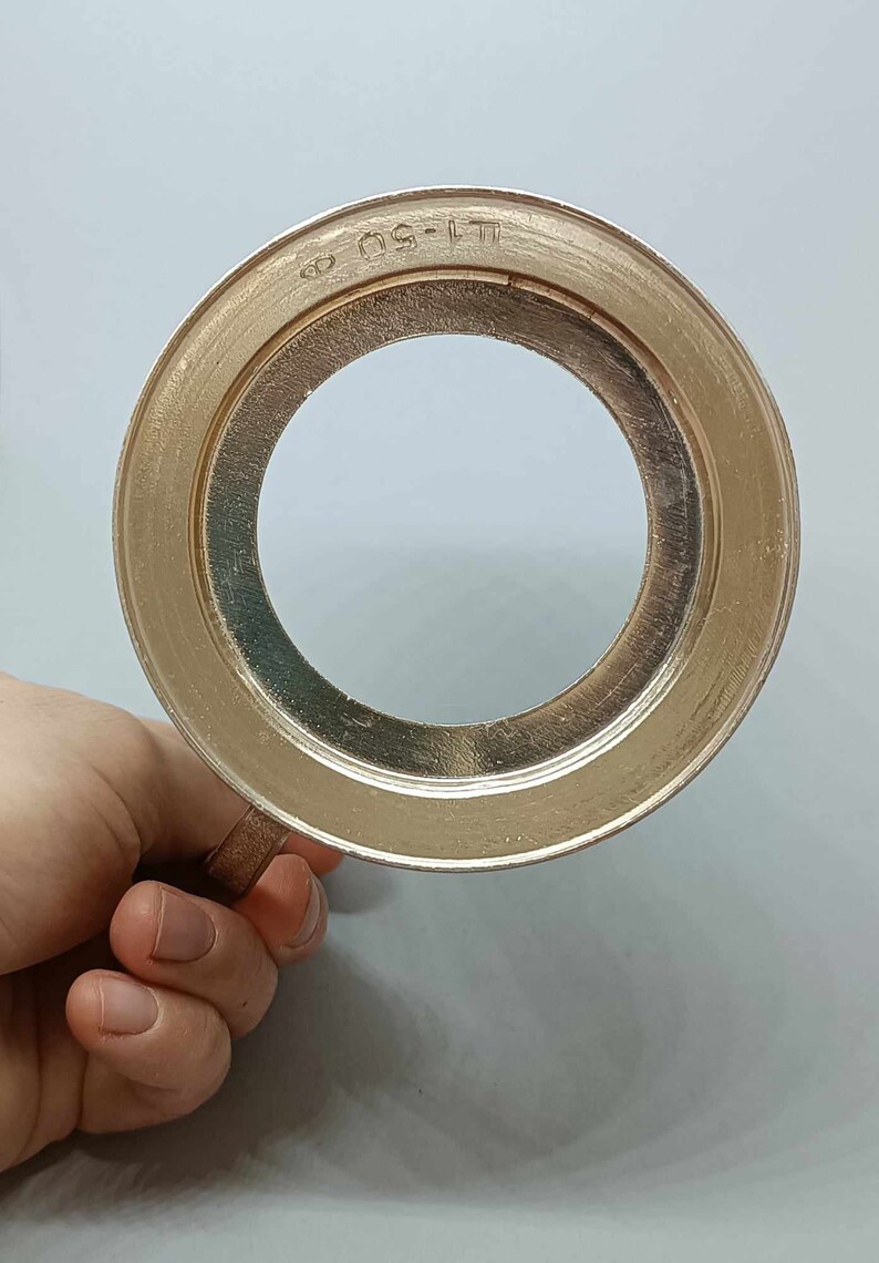 May include: A silver-colored metal ring with a circular opening and the text "LT-50" engraved on the outer edge.