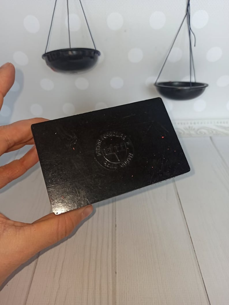 Puede incluir: Caja rectangular negra con un logotipo circular rojo que dice "Precision Ground" y "Made in England".