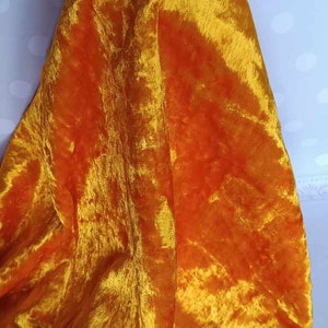 May include: A bright orange velvet fabric with a soft, plush texture. The fabric is folded and draped over a hand.