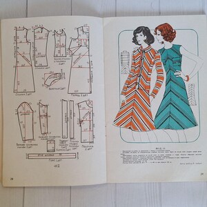 Op de afbeelding: Een vintage naaipatronenboekje met instructies en diagrammen voor het maken van een jurk. Het patroon is voor een jurk met een gestreept ontwerp in oranje en wit en een effen turquoise jurk. Het boekje is getiteld "Model 13".
