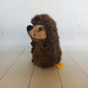 May include: A brown and black stuffed hedgehog toy with a yellow tag that says "Steiff 027714".