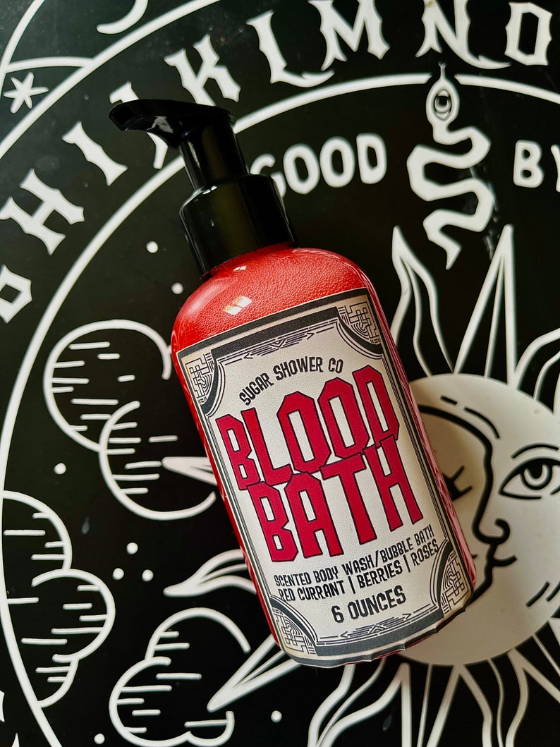 May include: A red bottle of "Blood Bath" scented body wash and bubble bath by Sugar Shower Co. The bottle is labeled with a black and white design and the text "Scented Body Wash/Bubble Bath Red Currant | Berries | Roses 6 Ounces".