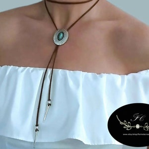 Modern western bolo tie necklace for women boho, ancient silver metal oval shape flower Concho with a marquise shape turquoise gemstone decoration slide over a 48 inch length cognac leather lace, silver spikes décor both ends of the leather lace.