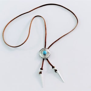 Western Bolo tie necklace for women girls, an Aztec style ancient silver metal round slider flower Concho with a oval shape turquoise gemstone decoration slide over a 34 inch length saddle tan leather lace, silver spikes décor both leather ends